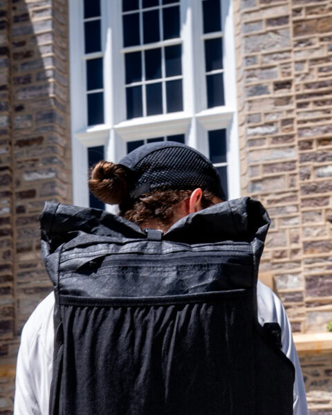 An urban explorer wears an ULA Ultra Node in front of a historic stone building. The roll-top is tightly rolled down.